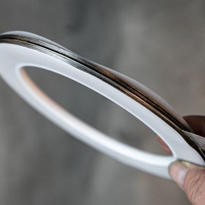 Mano sosteniendo una junta plana de PTFE de forma anular con capa metálica central