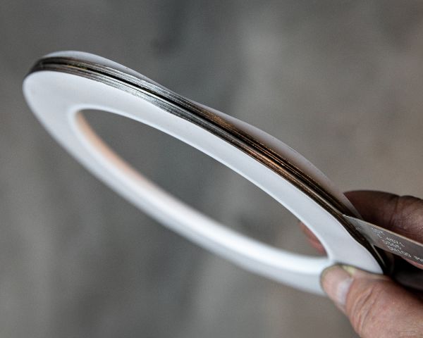 Mano sosteniendo una junta plana de PTFE de forma anular con capa metálica central