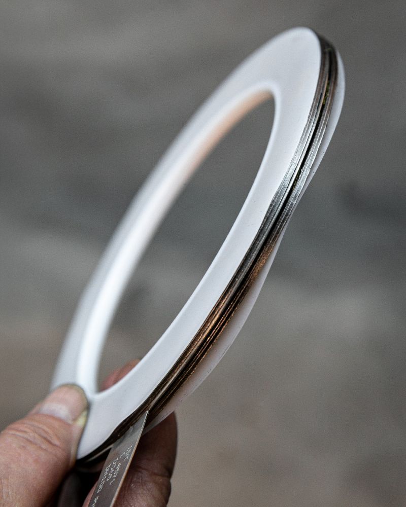 Mano sosteniendo una junta plana de PTFE de forma anular con capa metálica central